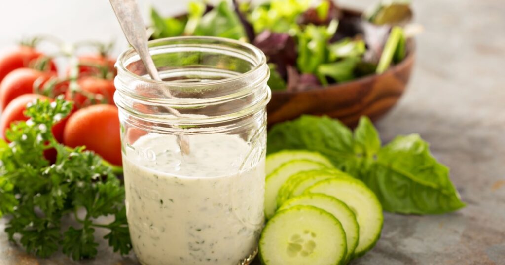 Homemade ranch dressing in a mason jar with fresh vegetables