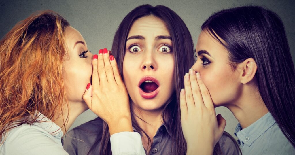Three young women telling whispering a secret gossip each other in the ear