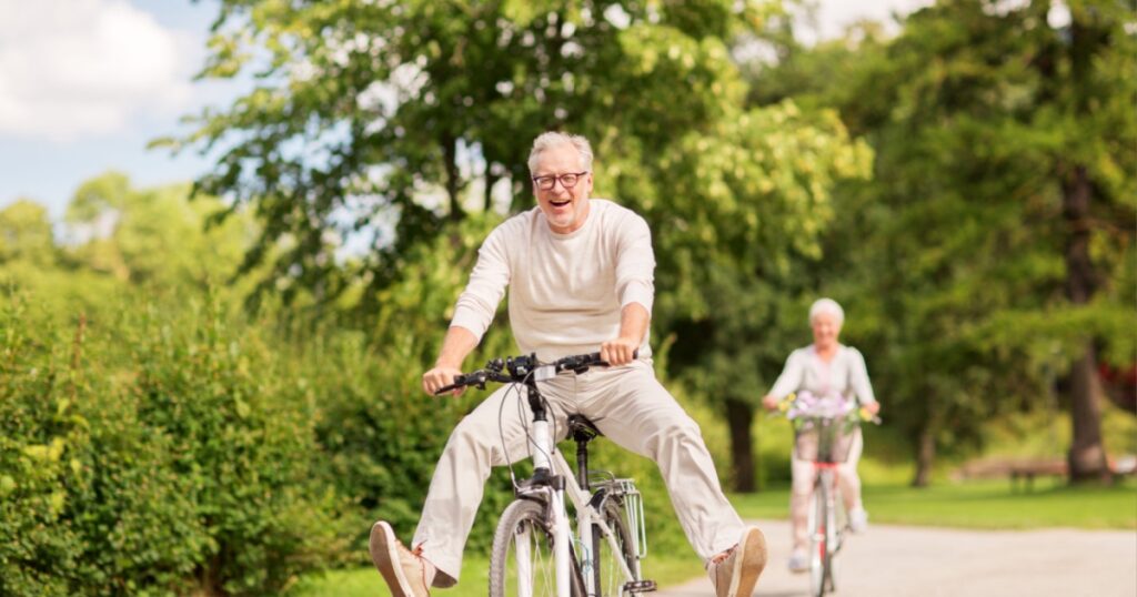 active old age, people and lifestyle concept - happy senior couple riding bicycles at summer park