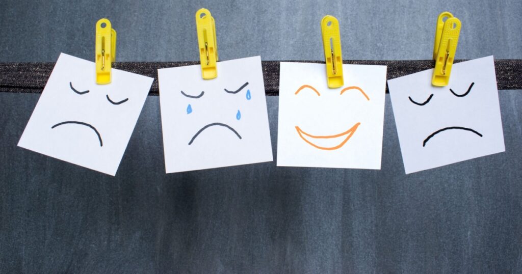 Optimist between pessimists, different emotions drawn on notes, dark background.