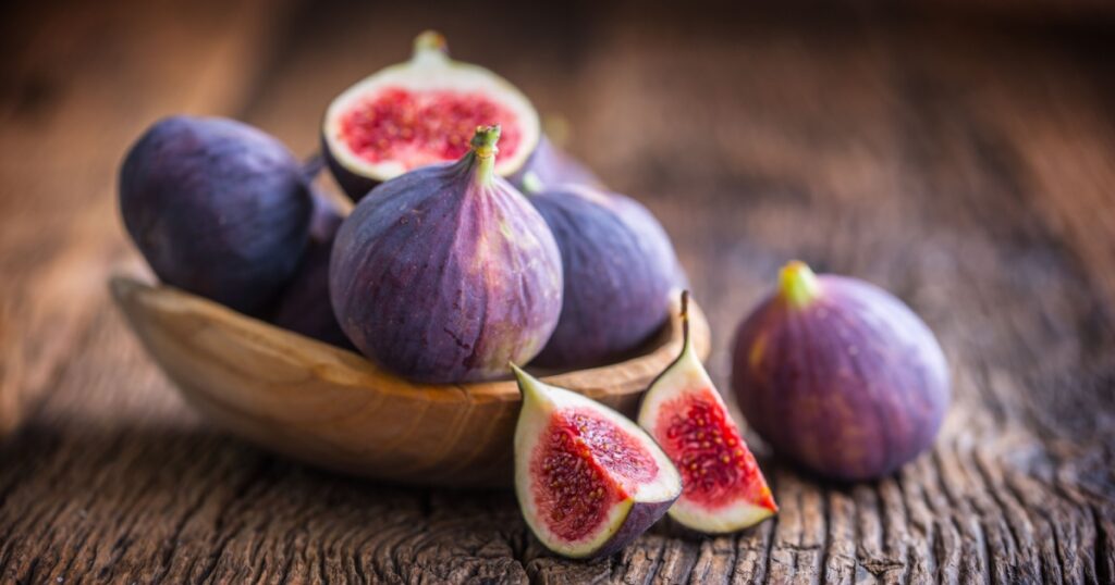 A few figs in a bowl on an old wooden background.