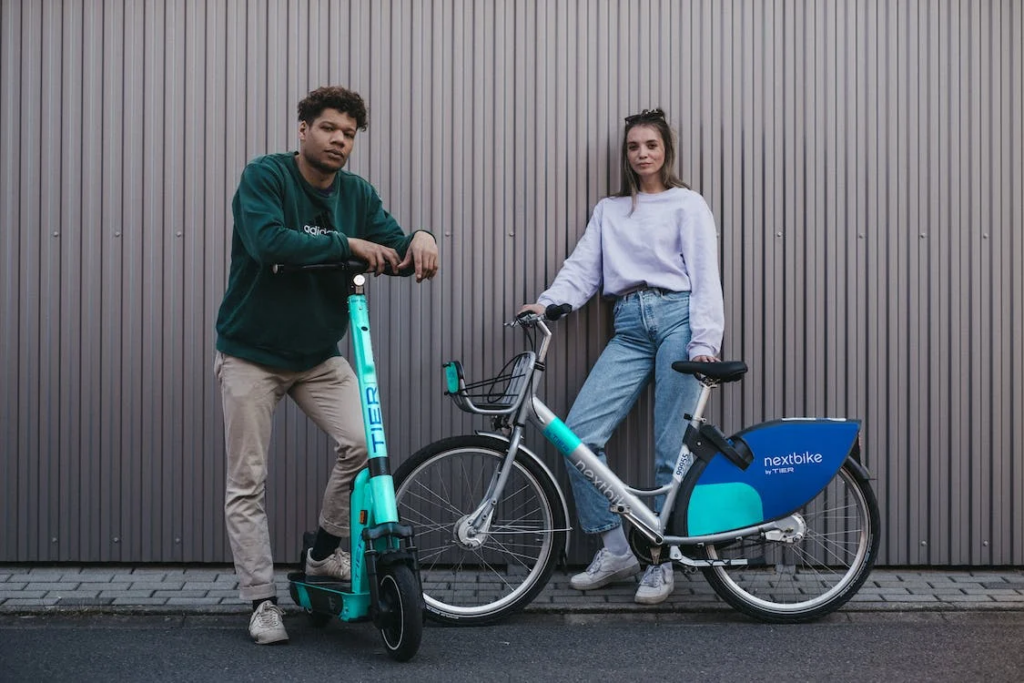 A Man and Woman Posing with an Electric Scooter and Electric Bicycle