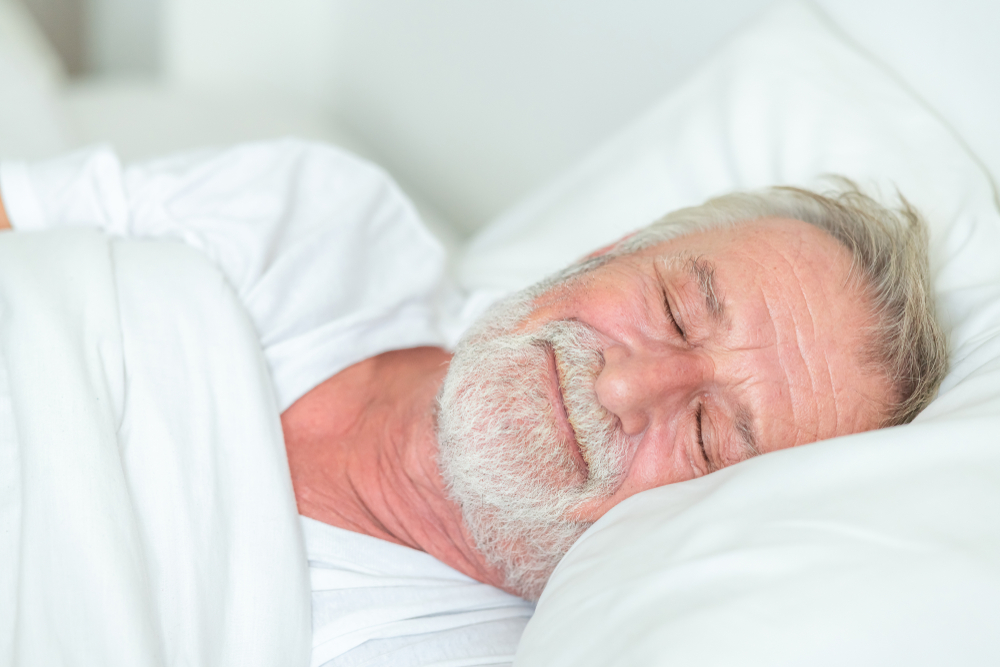 Happy senior man sleeping in bed. Smile.