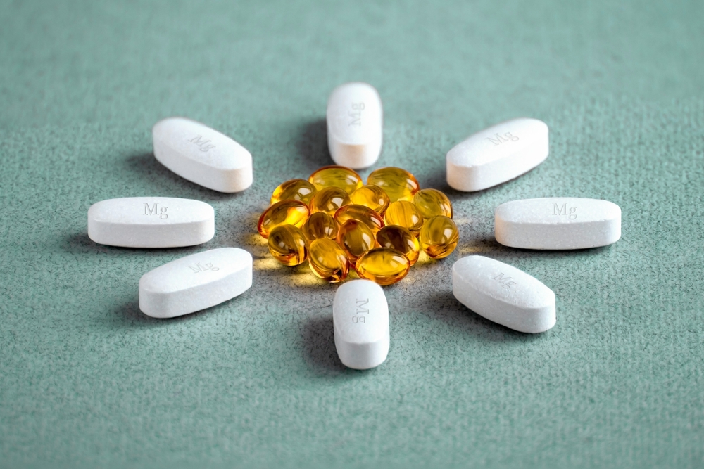 A complex of magnesia, magnesium, and vitamin D ( omega 3 ) capsules for treatment and human health, laid out in the shape of a flower on a light background.