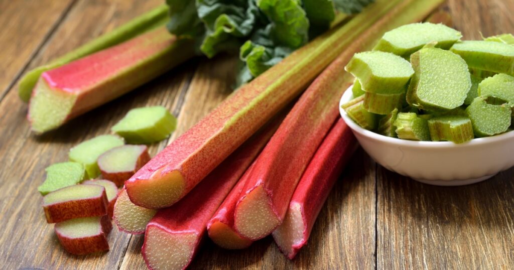 Rhubarb on wooden table. Fresh rhubarb on white bowl.