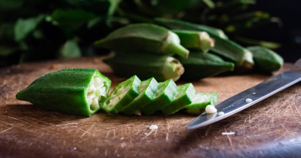 Raw Green Organic Okra Harvest Ready to Cook With. Close up Farm fresh okro on wooden rustic table. Lady Fingers or Okra over wooden surface Ochro, Malvaceae or mallow on dark background