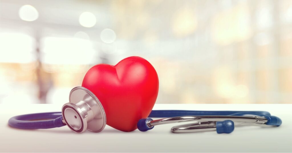 One single alone red heart love shape hand exercise ball with bandage MD medical doctor physician's stethoscope white wood background: Hospital life insurance concept: World heart health day idea