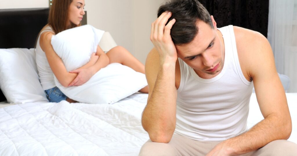 Upset man having problem sitting on the bed with his girlfriend