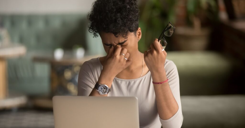 Overworked tired african female student worker holding glasses feel eye strain fatigue after computer work, mixed race woman suffer from pain in dry irritated eyes, bad blurry vision eyesight problem