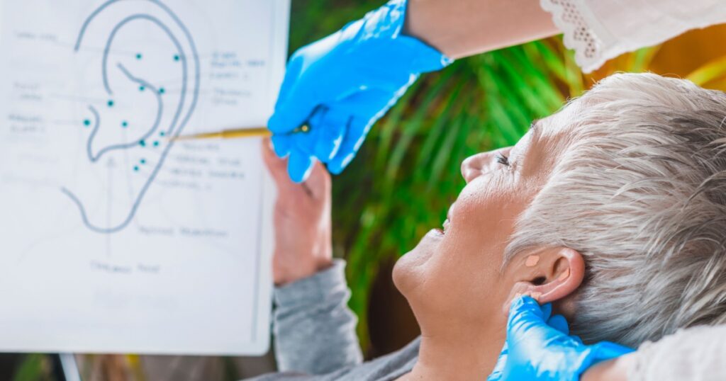 Patient learning about ear points in auriculotherapy treatment.