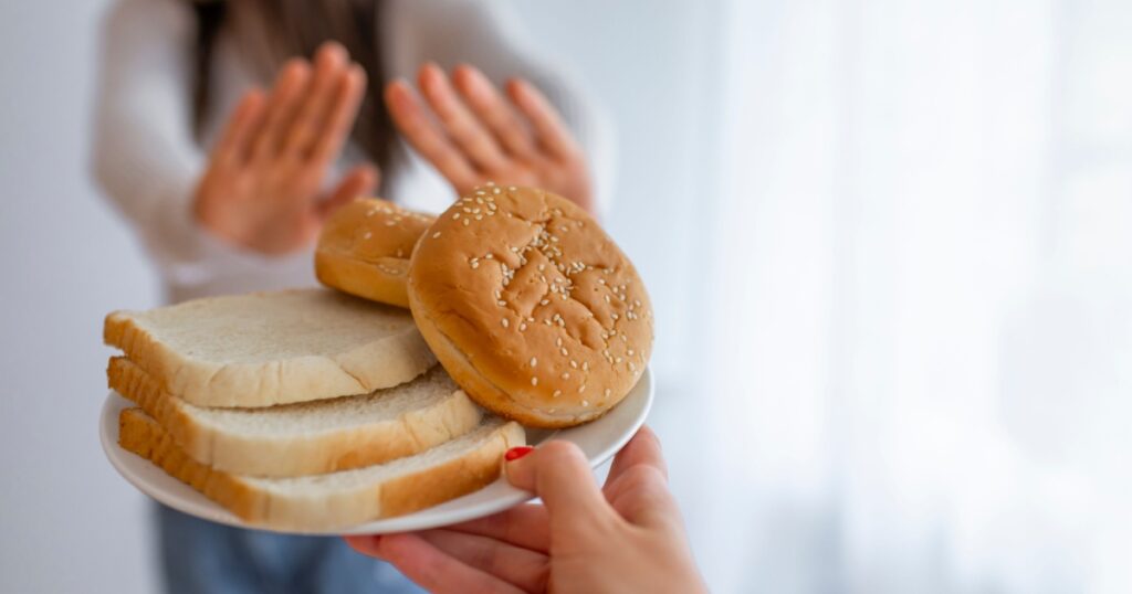 Woman suffers from a gluten. Gluten intolerant and Gluten free diet concept, Real people. Copy space. Gluten intolerance and diet concept. Woman refuses to eat white bread. Selective focus on bread
