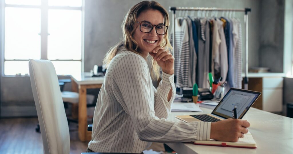 Smiling young woman taking note of orders from customers. Dropshipping business owner working in her office.