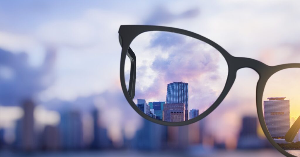 Modern bright city view through eyeglasses. Blurry background. Vision concept
