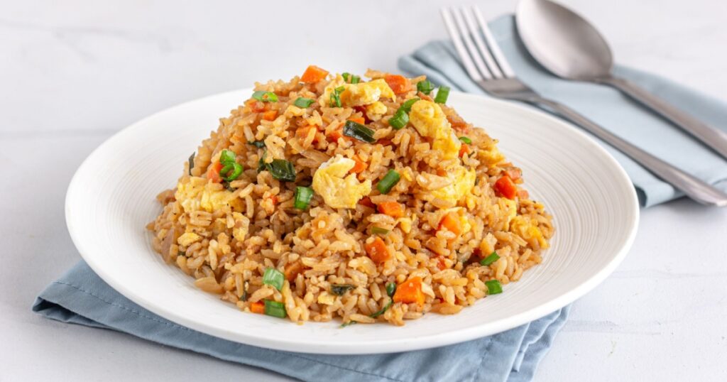 Chinese Asian Egg and Vegetable Fried Rice on a White Plate on the White Background.