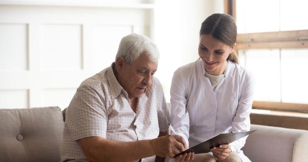 Smiling young female medical worker visit consult senior male patient sign health insurance contract, positive woman nurse or doctor close deal with mature man client, elderly healthcare concept
