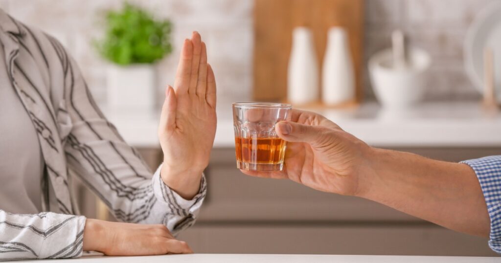 Woman refusing to drink whiskey at home. Concept of alcoholism