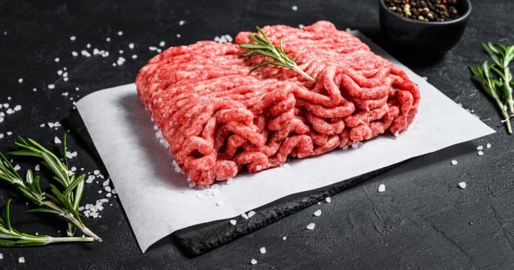 Raw minced pork. Black background. Top view. Space for text