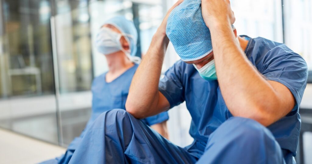 Two exhausted and desperate surgeons as signs of congestion and error