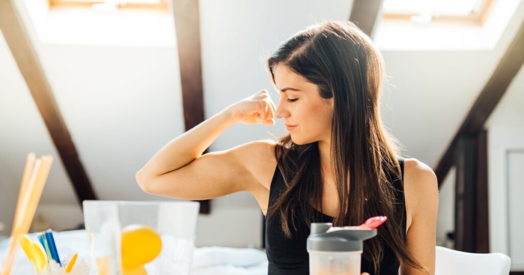 Woman at home drinking orange flavored amino acid vitamin powder.Keto supplement.After exercise liquid meal.Weight loss fitness nutrition diet.Immune system support.Organic citrus fruit drink