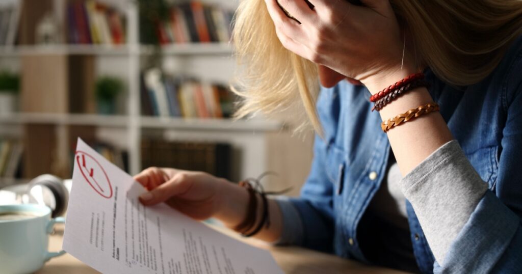 Close up of sad student complaining about failed exam sitting on a desk at home at night