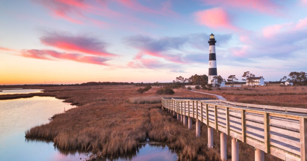 Clouds stream like pink ribbons in the sky over the marsh and lighthouse on Bodie Island on the Outer Banks of North Carolina.