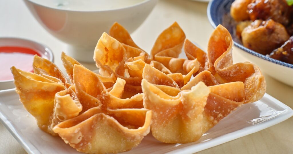 chinese crab rangoon fried wontons on plate with red sauce