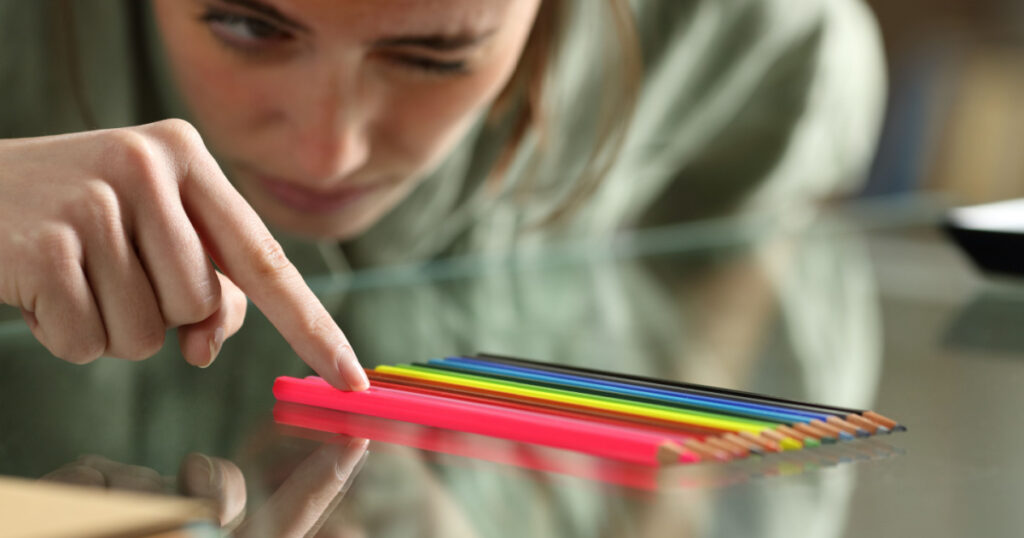 Obsessive compulsive woman aligning up pencils accurately on a glass table