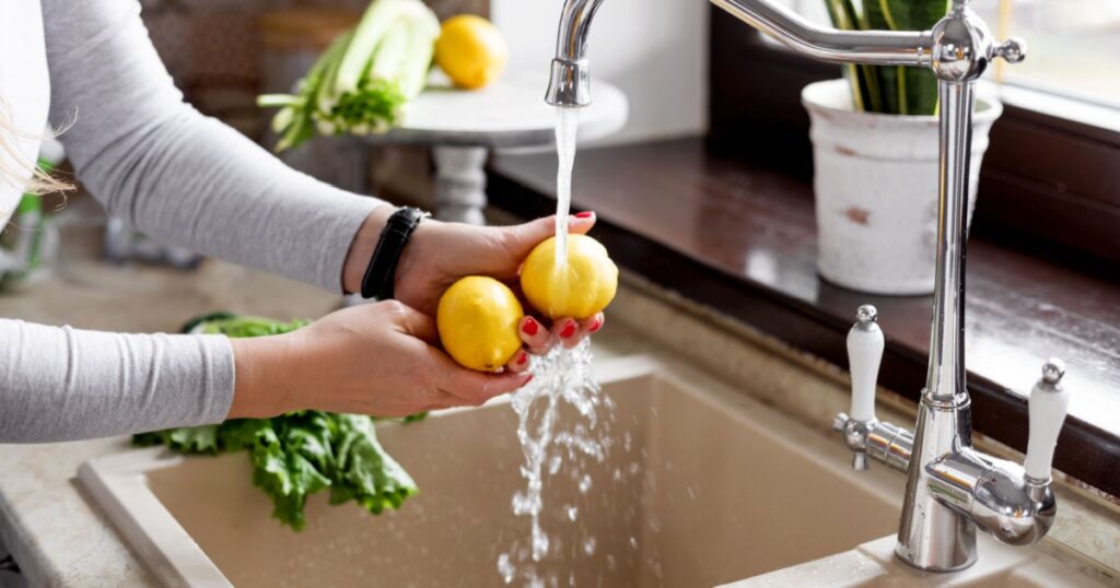 Close-up of a girl s hands washing a lemon in the sink in a home kitchen. The concept of health and a healthy lifestyle. Healthy eating, diet, vegetarianism
