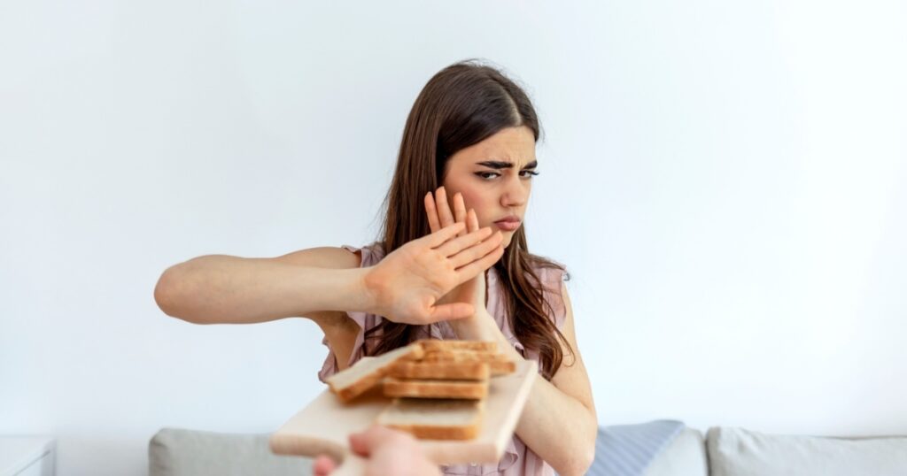Cropped shot of a young woman on a gluten free diet is saying no thanks to white bread. Woman refusing to eat white bread. Gluten intolerance concept. Health care and medicine concept. Copy space.