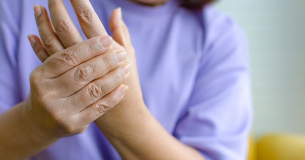 Woman using hand to hold other her palm with feeling pain, hurt and tingling. Concept of Guillain barre syndrome and numb hands disease.