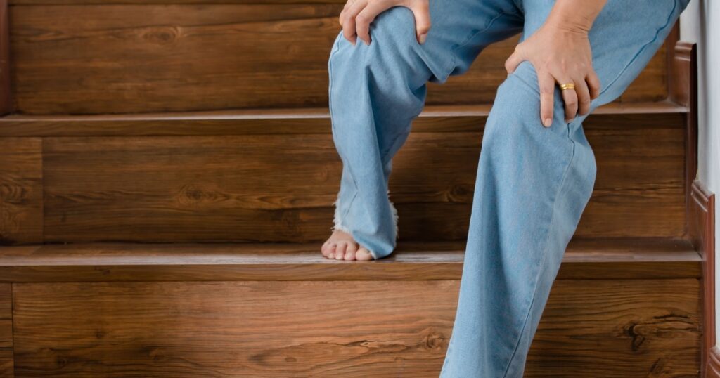 Woman stops for rest and leaning on wall for support while she cannot climb stairs with tingling legs. Concept of Guillain barre syndrome and numb legs disease or vaccine side effect.