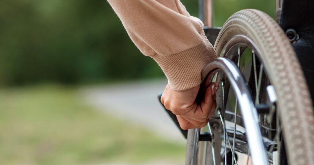 Close-up of a hand on a wheelchair wheel. The concept of a wheelchair, disabled person, full life, paralyzed, disabled person, happy life