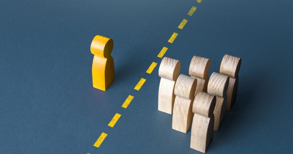 A person and a group of people are separated by a yellow line. Establishing contact. Distrust. Quarantine. Distance with strangers. Barrier to understanding, difficult integration. Rejection,