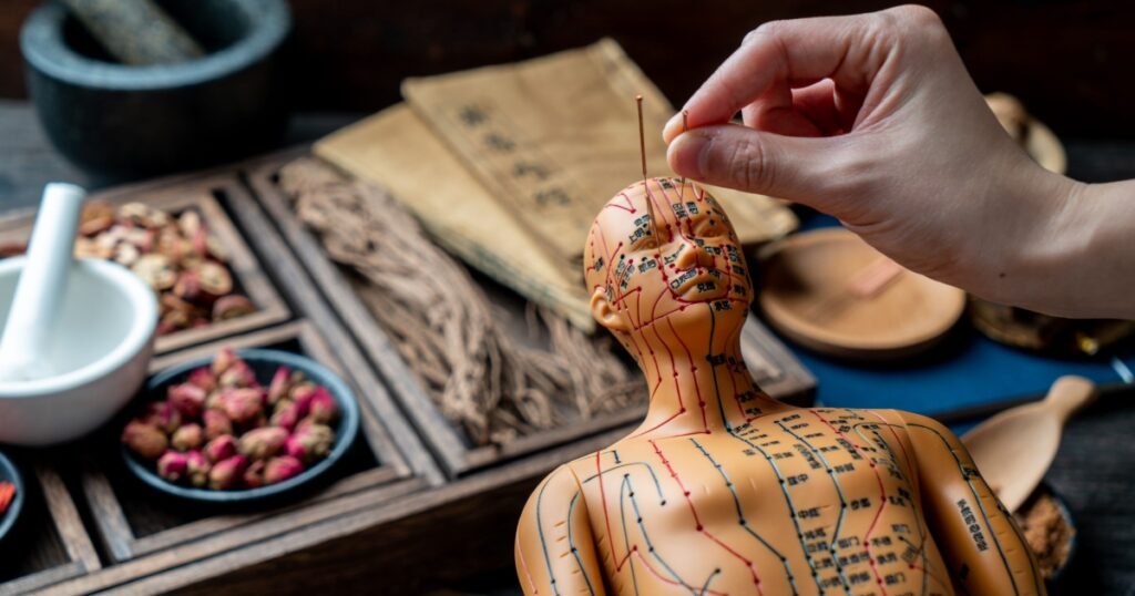 The doctor is pricking acupuncture with a model.Chinese character translation：Drawing acupuncture
