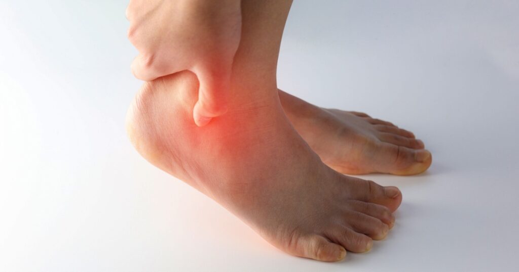 A person holding ankle on Achilles tendon, suffering with pain in red spot area. Sprain ligament or Achilles tendonitis symptoms. Image with red highlights on hurting area, Health care concept