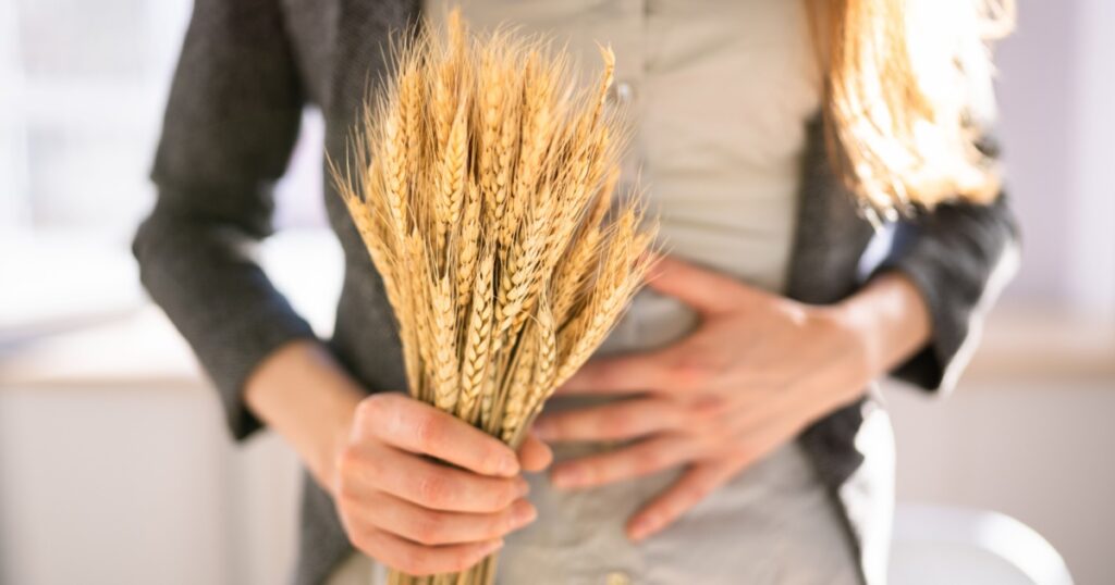 Celiac Disease And Gluten Intolerance. Women Holding Spikelet Of Wheat
