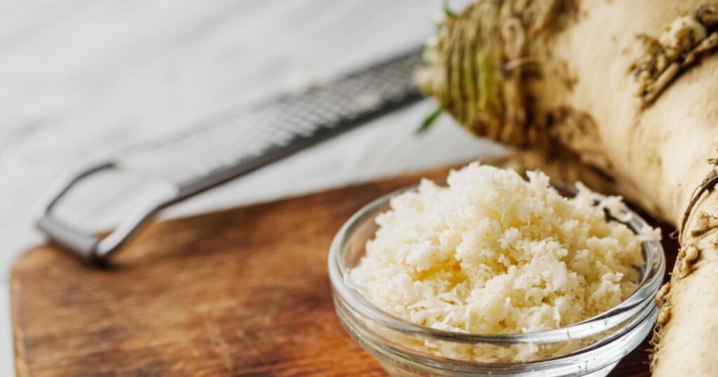 aromatic horseradish root on a white rustic wooden background.