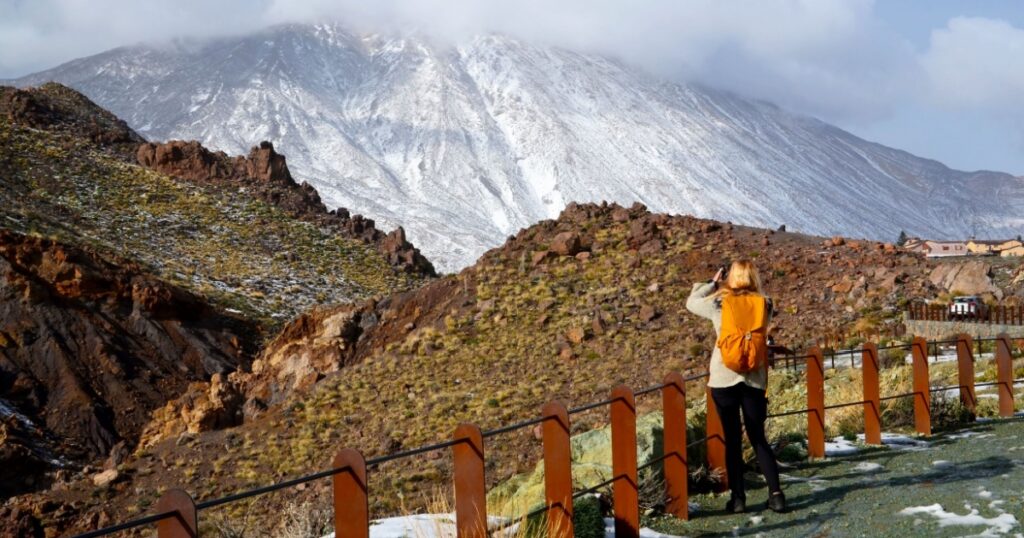 Winter in Teide National Park. Nature photographer taking pictures of Teide volcano covered with snow. Tenerife, Canary Islands, Spain. Selective focus.