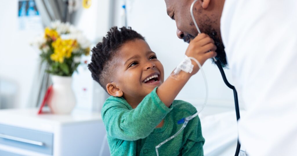 Laughing african american boy patient taking male doctor's stethoscope in hospital. Hospital, medical and healthcare services.