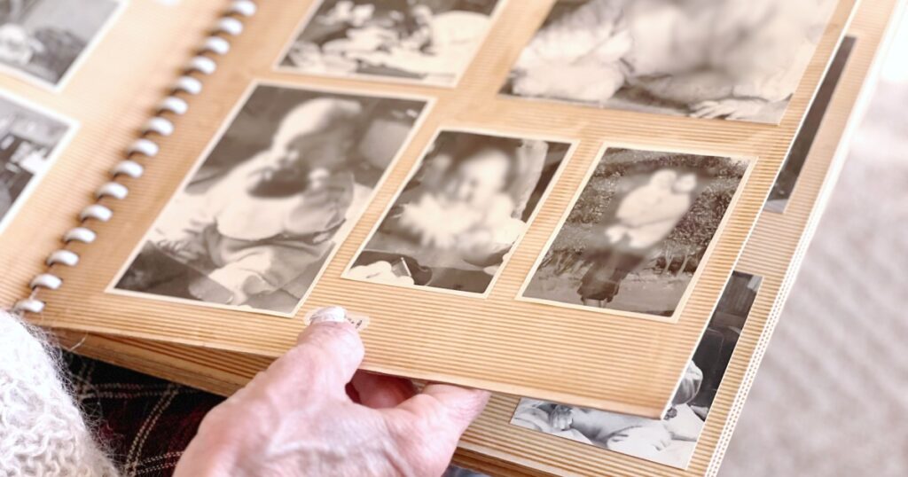 Elderly woman's hand looking at black and white photo album