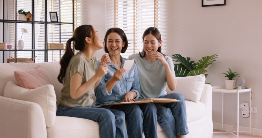 Recall the past life memories Happy time Mother's day grown up kid child joy fun look at old retro photo album with mature mum. Asia adult people middle age mom smile enjoy relax sitting at home sofa.