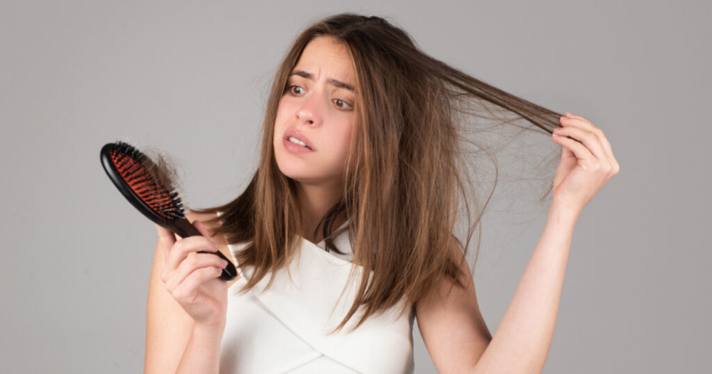 Woman hand holding comb with serious hair loss problem for health care shampoo.