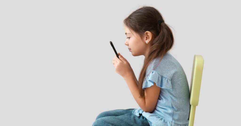 Little girl with bad posture using mobile phone on light background