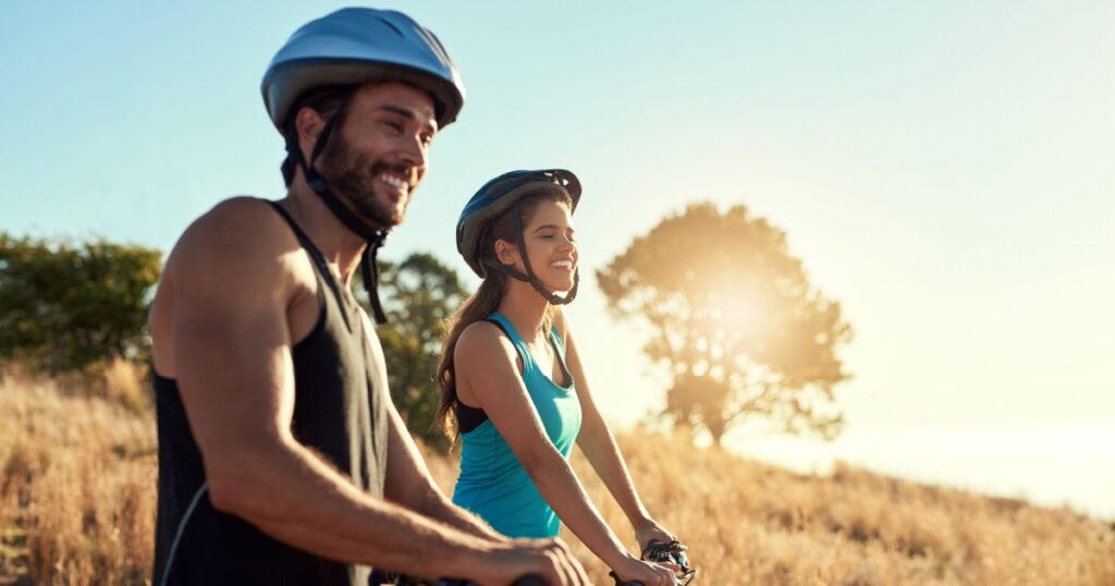 Happy couple, nature and cycling in the mountains for fitness and exercise together. Bike, wellness and young people with outdoor adventure and sports training with happiness and freedom mockup
