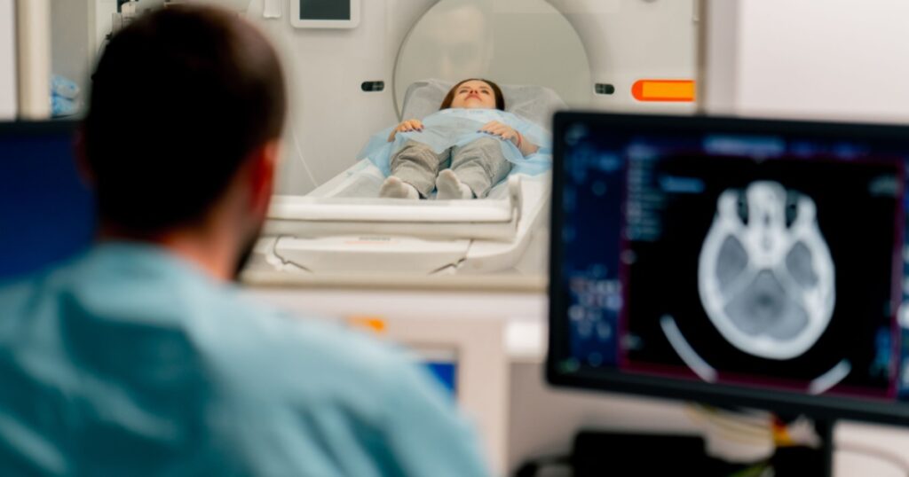 A girl lies on an MRI machine before examining her body and the radiologist gives command to her to prepare for a diagnosis