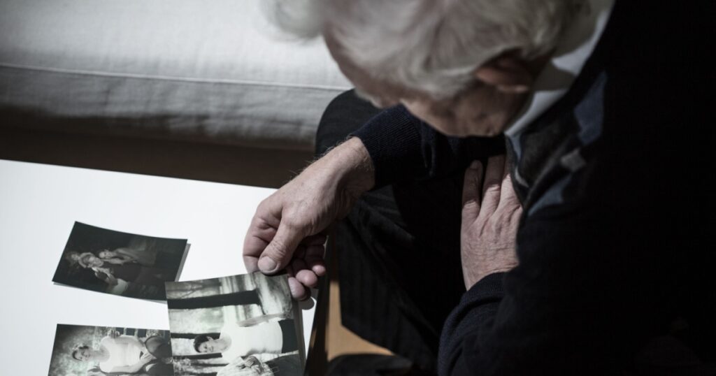 Senior depressed man looking at old photos