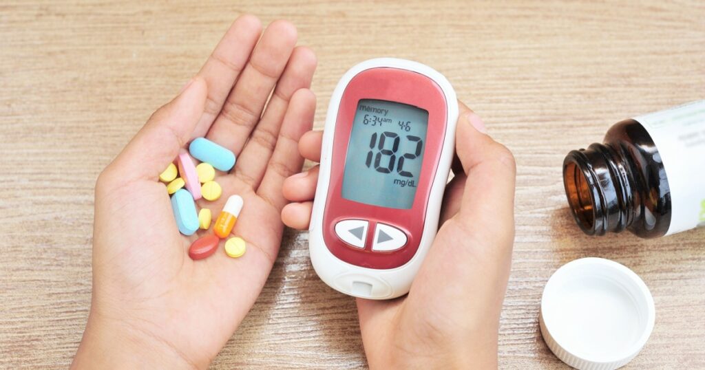 Hands hold glucometer and medicine.