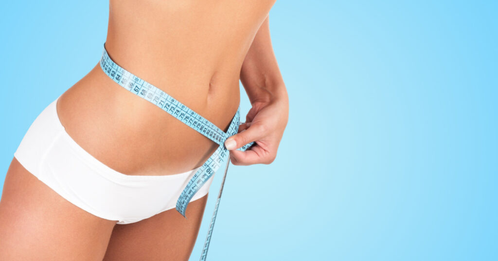 Beautiful woman measuring her waist - high key shot in studio