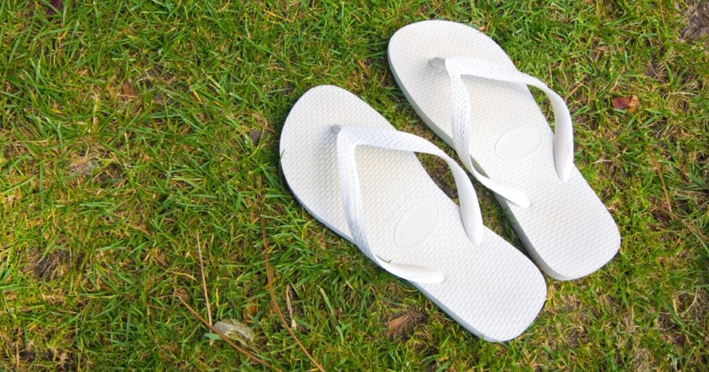 pair of white flipflops in grass background