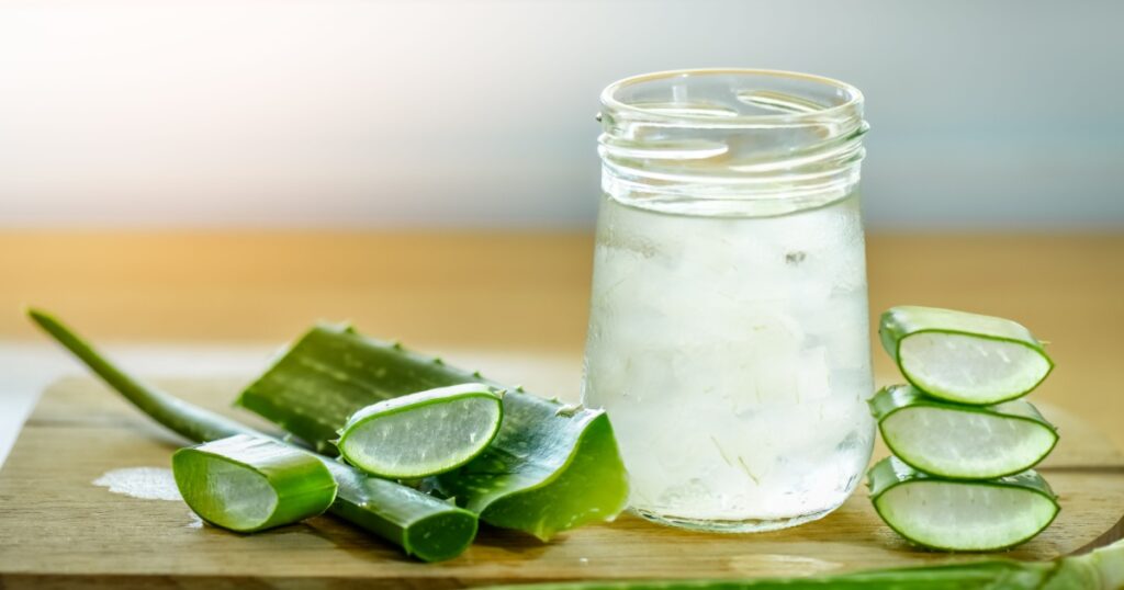 fresh aloe vera leaves and glass of aloe vera juice on wooden background